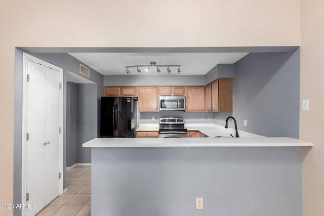 kitchen with kitchen peninsula, appliances with stainless steel finishes, light tile patterned floors, and sink