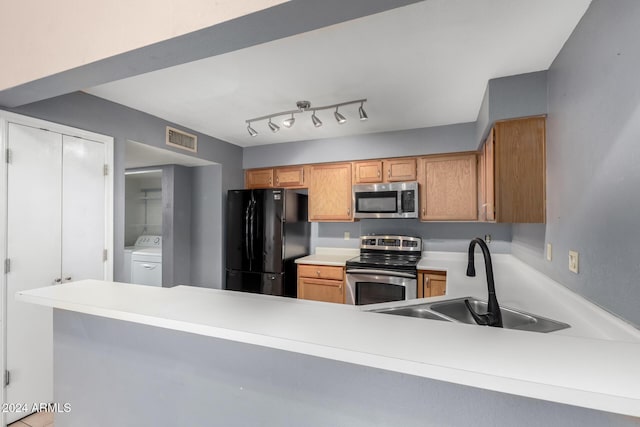 kitchen with kitchen peninsula, appliances with stainless steel finishes, washer / clothes dryer, and sink