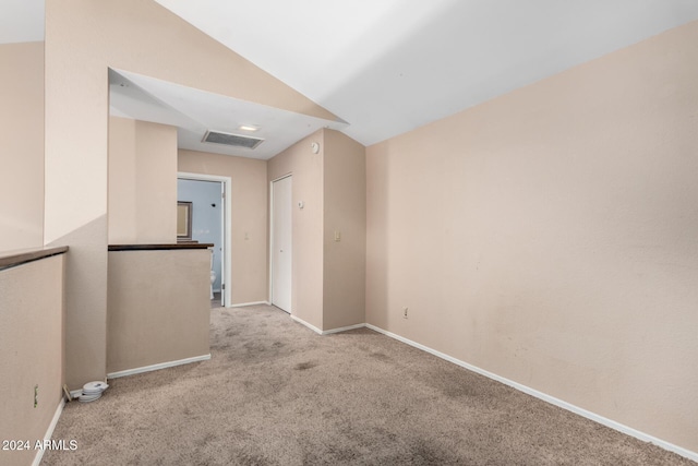 carpeted empty room with vaulted ceiling