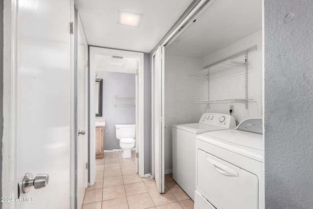 clothes washing area with light tile patterned floors and separate washer and dryer