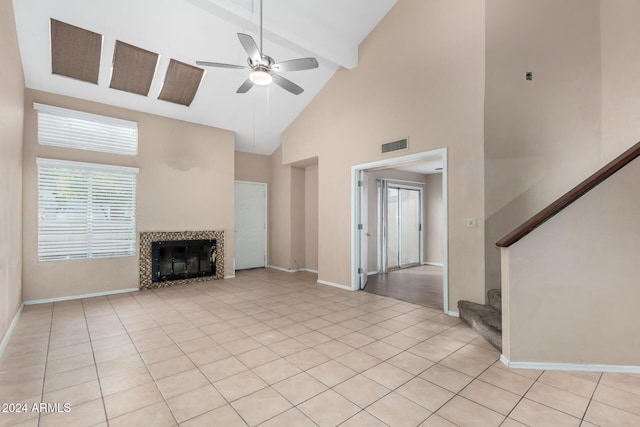 unfurnished living room featuring ceiling fan, beamed ceiling, high vaulted ceiling, a tiled fireplace, and light tile patterned floors