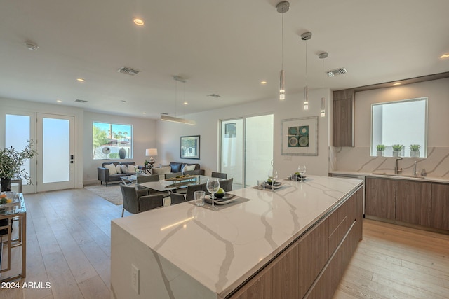 kitchen featuring decorative backsplash, light hardwood / wood-style flooring, a kitchen island, and light stone counters