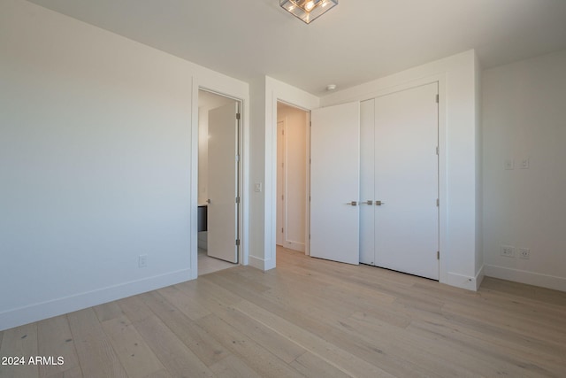 unfurnished bedroom with light wood-type flooring and a closet