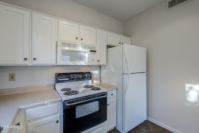 kitchen with white cabinetry, dark tile patterned floors, and white appliances