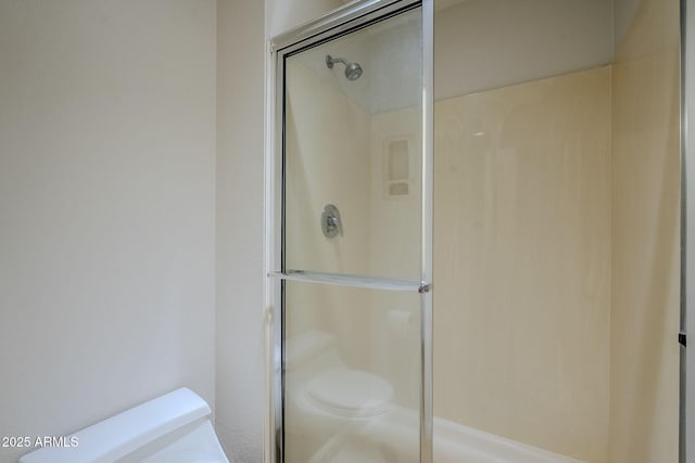 bathroom featuring a shower with shower door and toilet