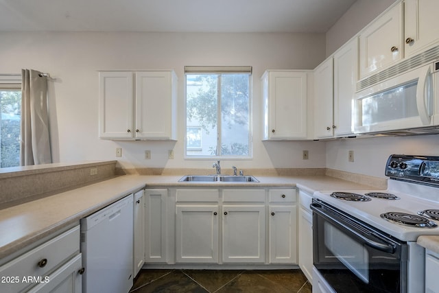 kitchen featuring white appliances, white cabinetry, dark tile patterned floors, and sink