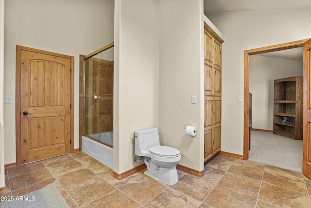 bathroom featuring combined bath / shower with glass door and toilet