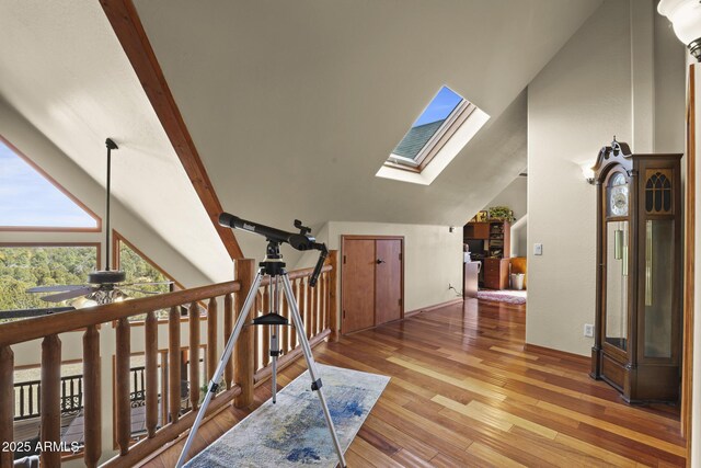 corridor with vaulted ceiling with skylight and light hardwood / wood-style floors