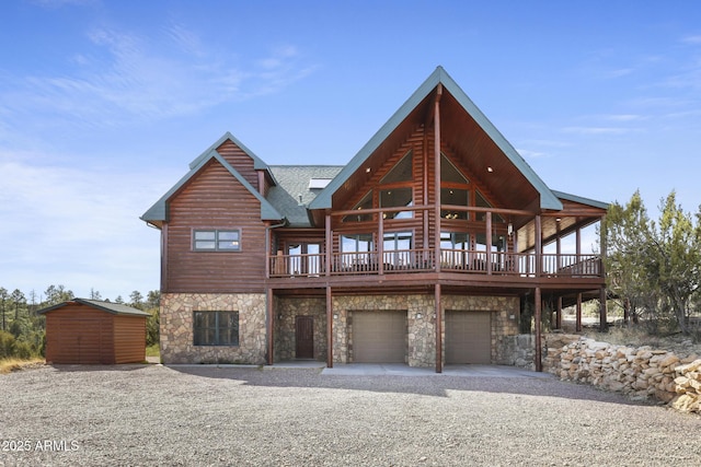 rear view of property with a shed, a wooden deck, and a garage