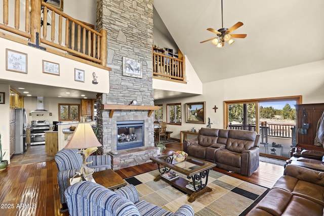 living room featuring hardwood / wood-style flooring, a fireplace, high vaulted ceiling, and ceiling fan