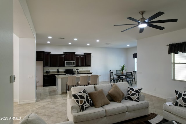 living room featuring sink, light tile patterned floors, and ceiling fan