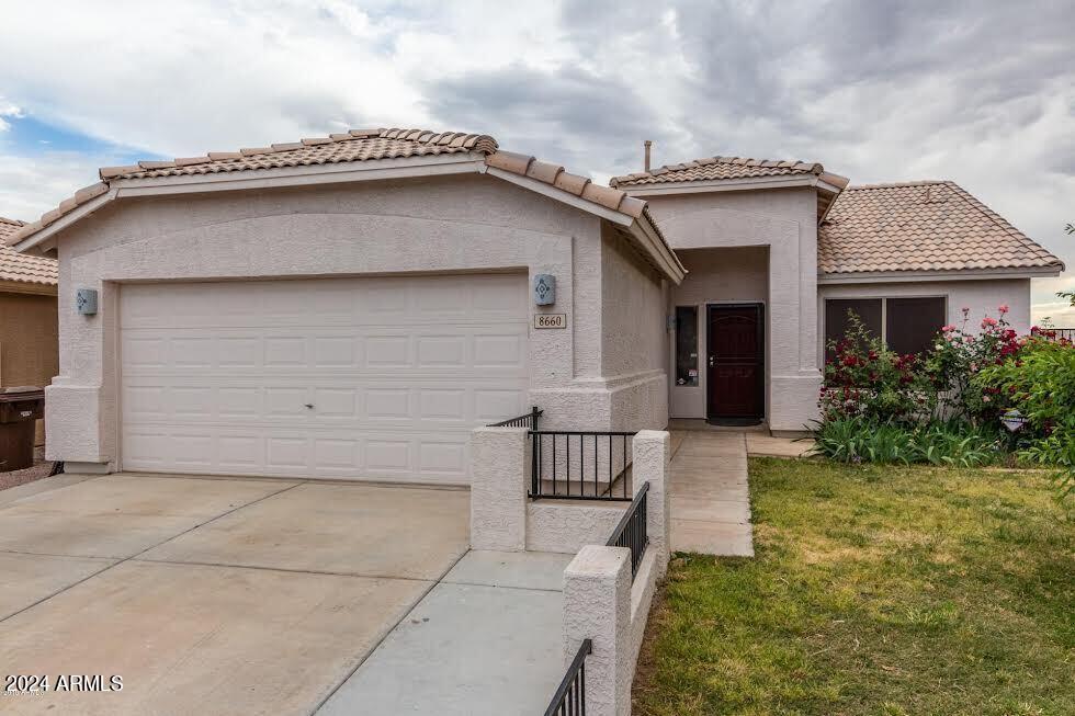 mediterranean / spanish home featuring a garage and a front lawn