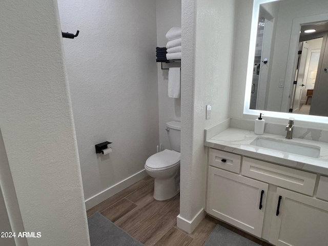 bathroom with toilet, vanity, and hardwood / wood-style floors