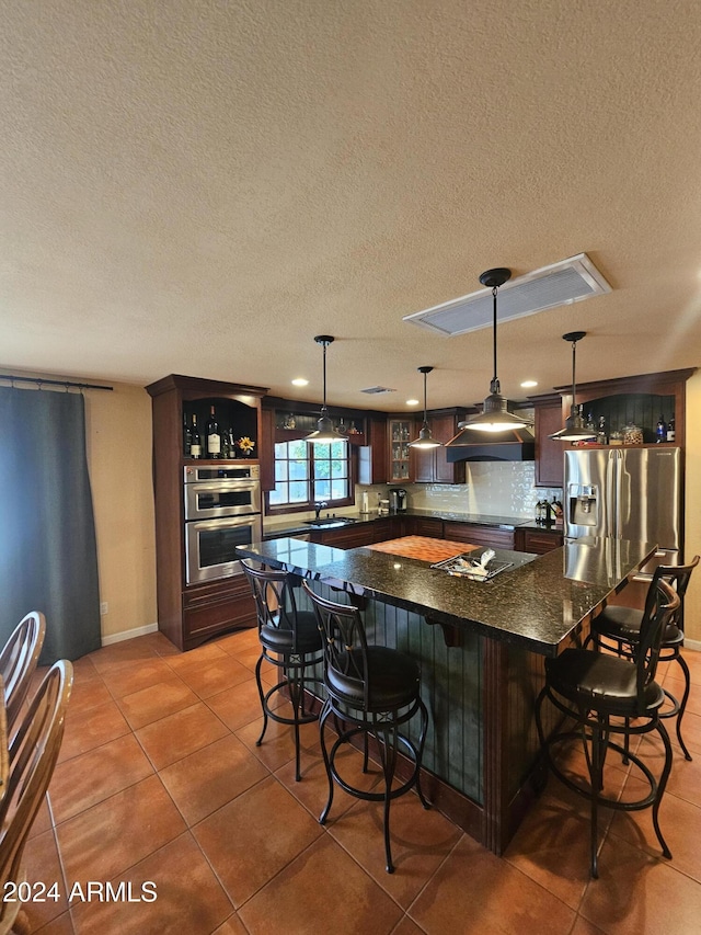 kitchen featuring hanging light fixtures, a kitchen bar, a center island, and appliances with stainless steel finishes