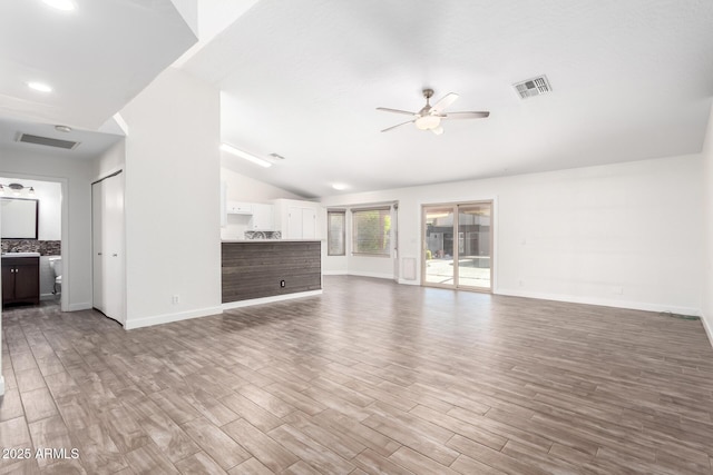 unfurnished living room with ceiling fan, vaulted ceiling, and wood-type flooring