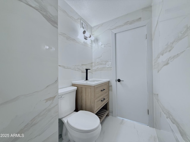 bathroom with vanity, visible vents, a textured ceiling, toilet, and marble finish floor