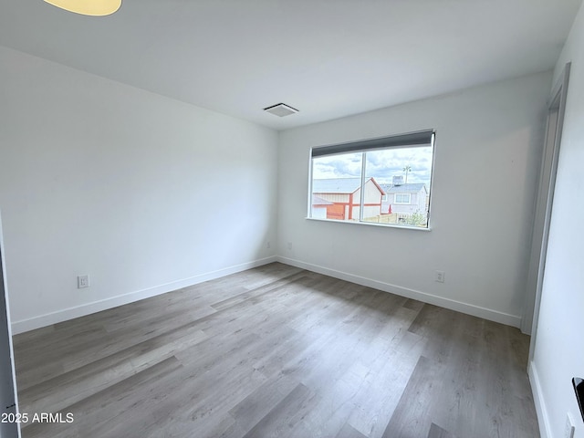 spare room with visible vents, wood finished floors, and baseboards