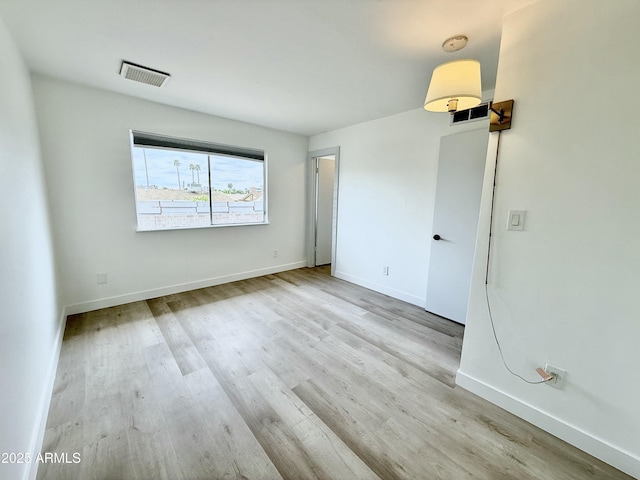 unfurnished room featuring visible vents, baseboards, and wood finished floors