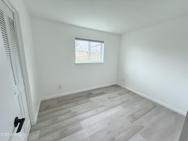 unfurnished bedroom featuring light wood-style floors, baseboards, and a closet