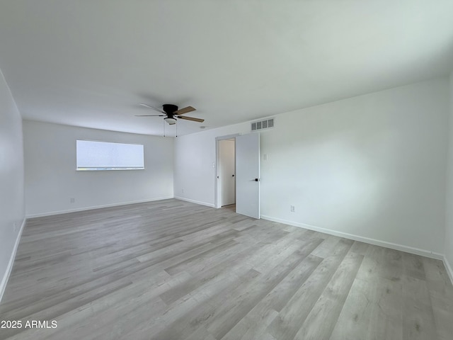 spare room featuring light wood-type flooring, visible vents, baseboards, and a ceiling fan