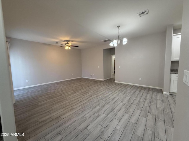 empty room with light hardwood / wood-style floors and ceiling fan with notable chandelier