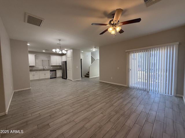 unfurnished living room with sink, ceiling fan with notable chandelier, and light wood-type flooring