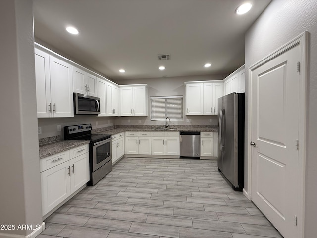 kitchen featuring stone countertops, appliances with stainless steel finishes, sink, and white cabinets