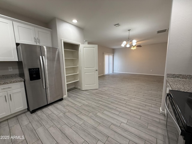 kitchen featuring stainless steel refrigerator with ice dispenser, white cabinetry, light stone countertops, and electric range oven