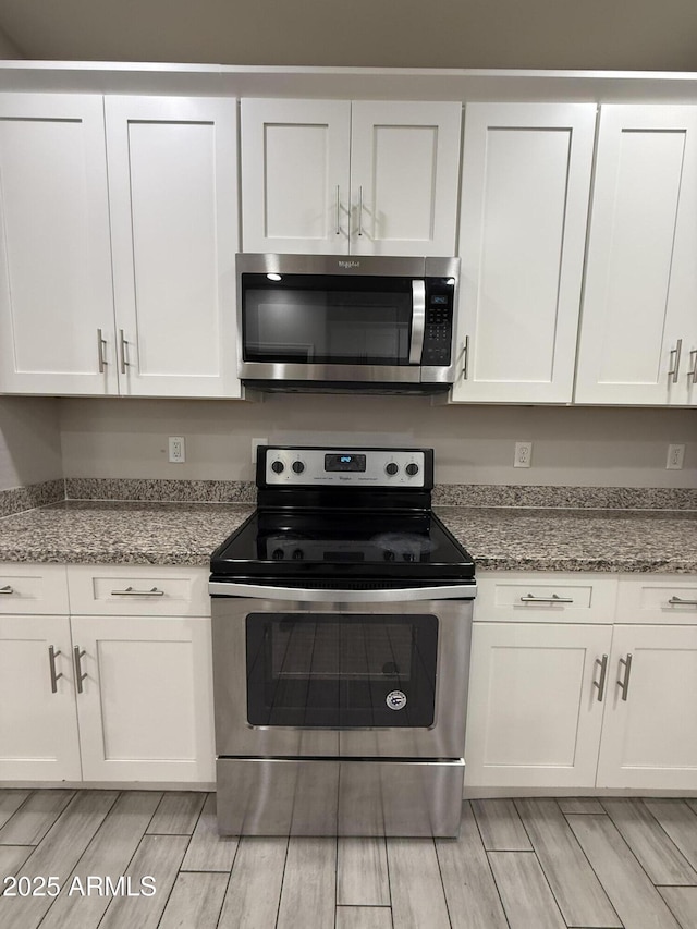 kitchen with stainless steel appliances, light stone countertops, and white cabinets