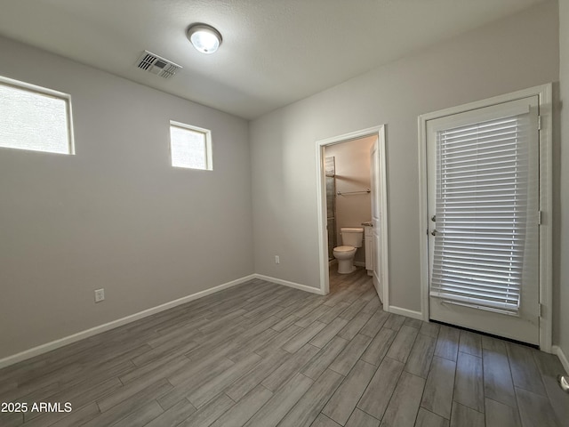 unfurnished bedroom featuring connected bathroom and light hardwood / wood-style flooring