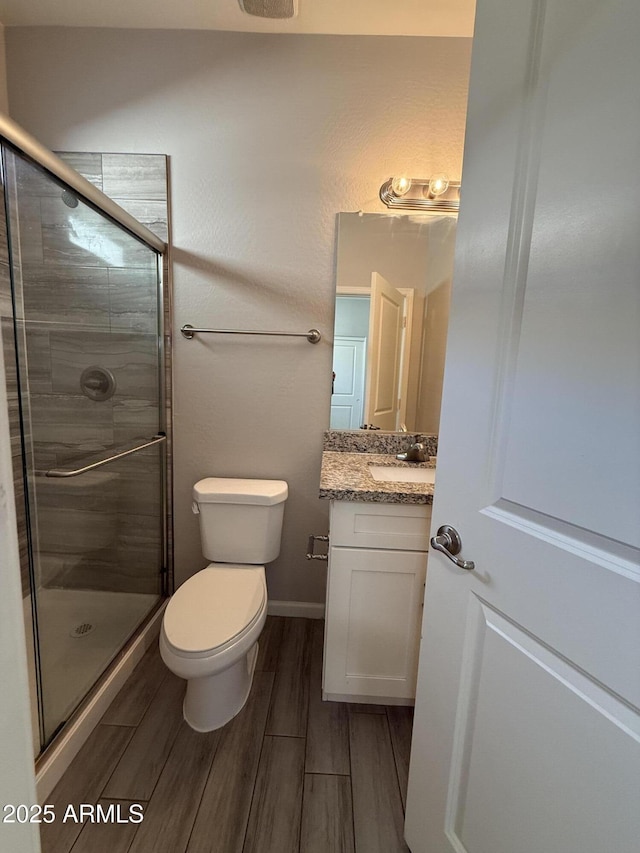 bathroom featuring vanity, an enclosed shower, and toilet