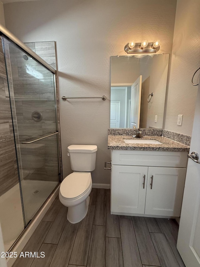 bathroom with a shower with door, vanity, and toilet