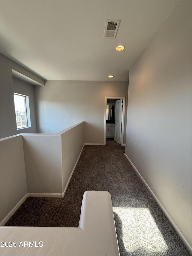 hallway featuring dark colored carpet