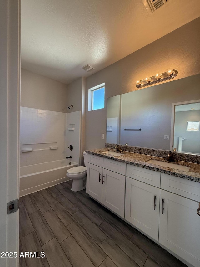 full bathroom with washtub / shower combination, vanity, toilet, and a textured ceiling