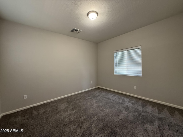 spare room with a textured ceiling and dark colored carpet