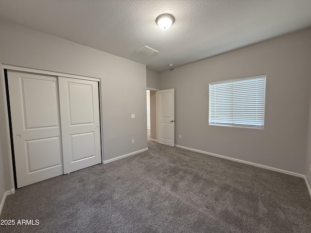 unfurnished bedroom with carpet flooring, a textured ceiling, and a closet