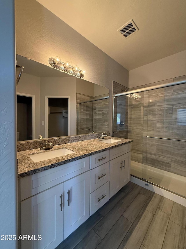 bathroom featuring vanity and a shower with door