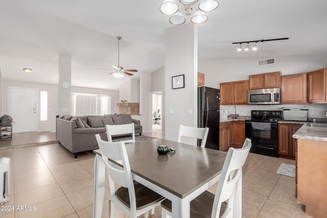 tiled dining area with sink, vaulted ceiling, rail lighting, and ceiling fan