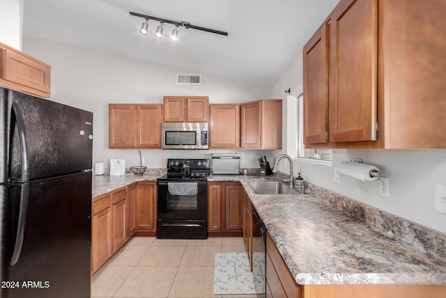 kitchen featuring sink, light tile patterned floors, black appliances, and vaulted ceiling