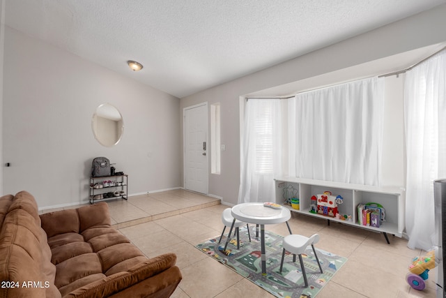 living room featuring vaulted ceiling, a textured ceiling, and light tile patterned floors