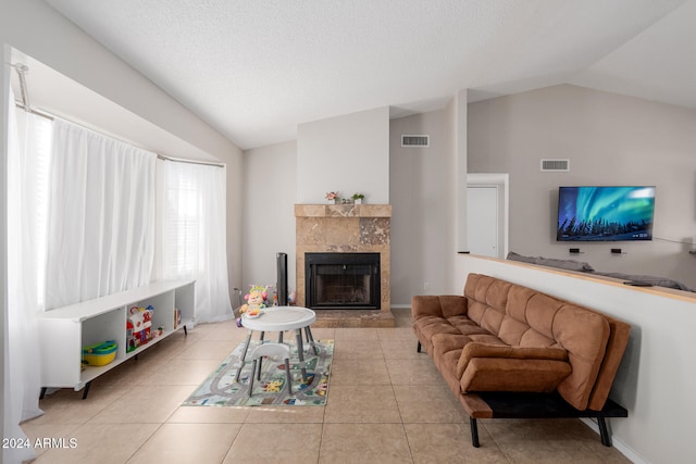 living room with lofted ceiling, a textured ceiling, a tile fireplace, and light tile patterned floors