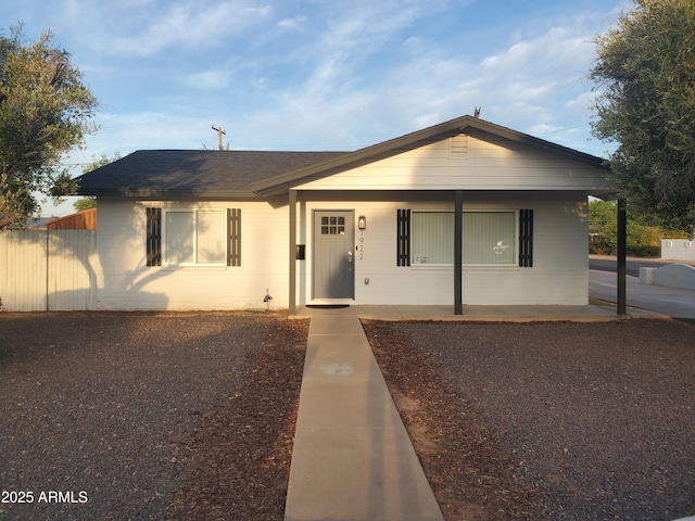 view of front of home with covered porch, fence, and a shingled roof