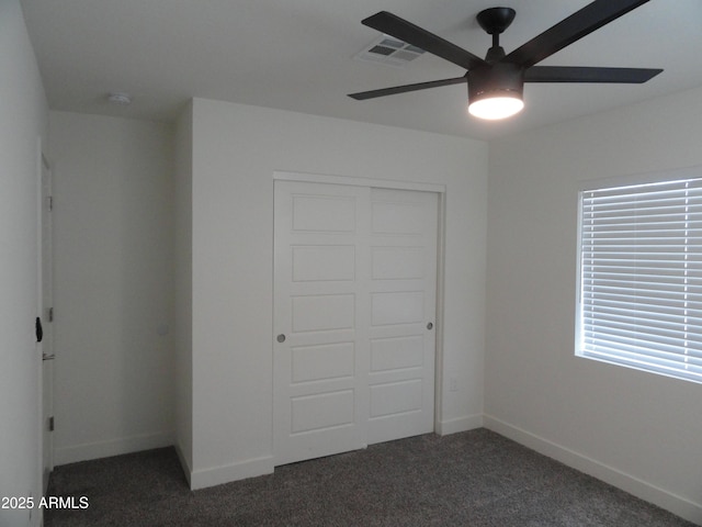 unfurnished bedroom featuring carpet flooring, a closet, baseboards, and a ceiling fan