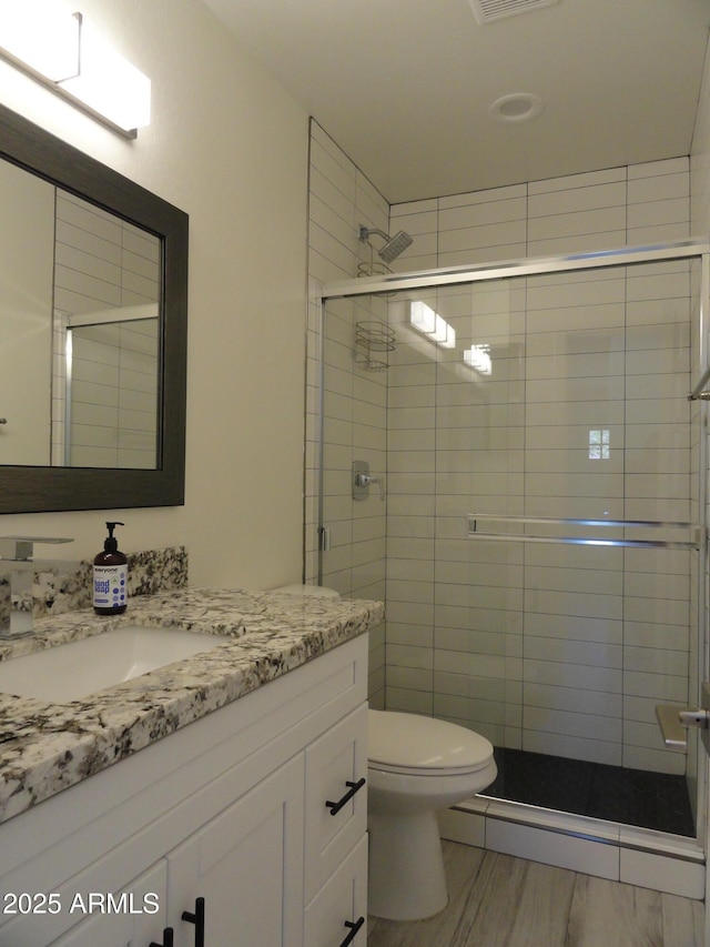 full bathroom featuring a shower stall, vanity, and toilet