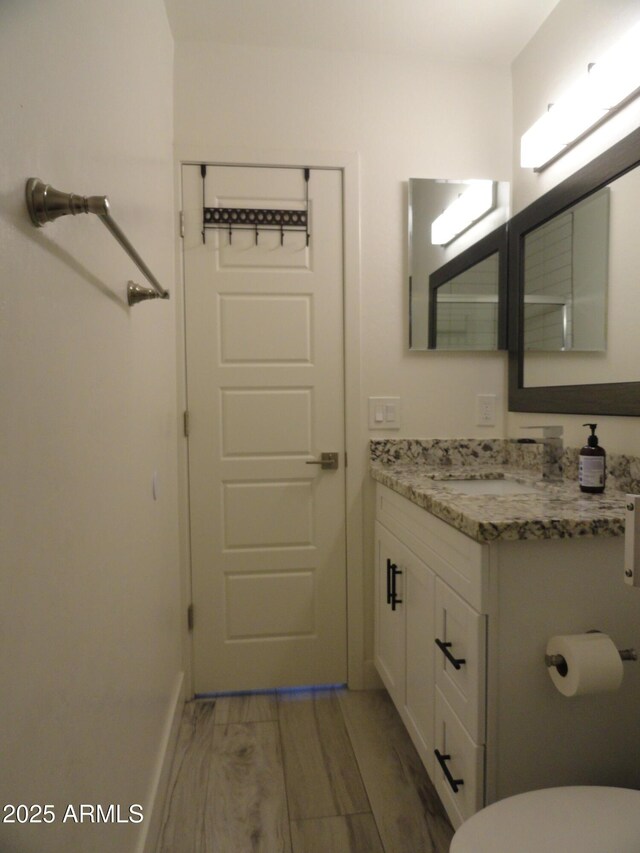 half bathroom with vanity, toilet, and baseboards