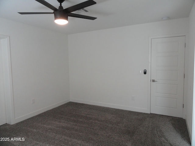 spare room with dark colored carpet, ceiling fan, and baseboards