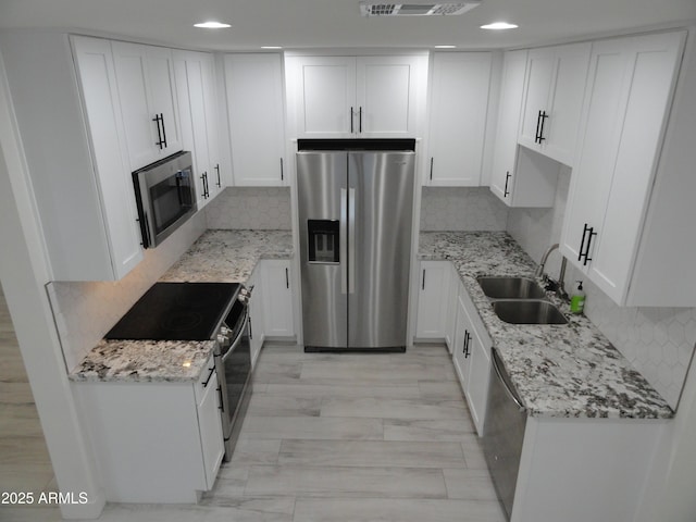 kitchen with stainless steel appliances, a sink, white cabinetry, and recessed lighting