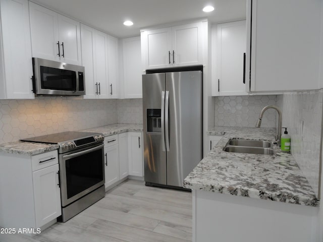 kitchen with appliances with stainless steel finishes, a sink, tasteful backsplash, light stone counters, and recessed lighting