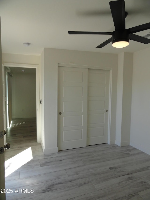 unfurnished bedroom with a closet, wood finished floors, baseboards, and ceiling fan