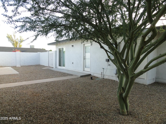back of house featuring a fenced backyard, a patio, and stucco siding
